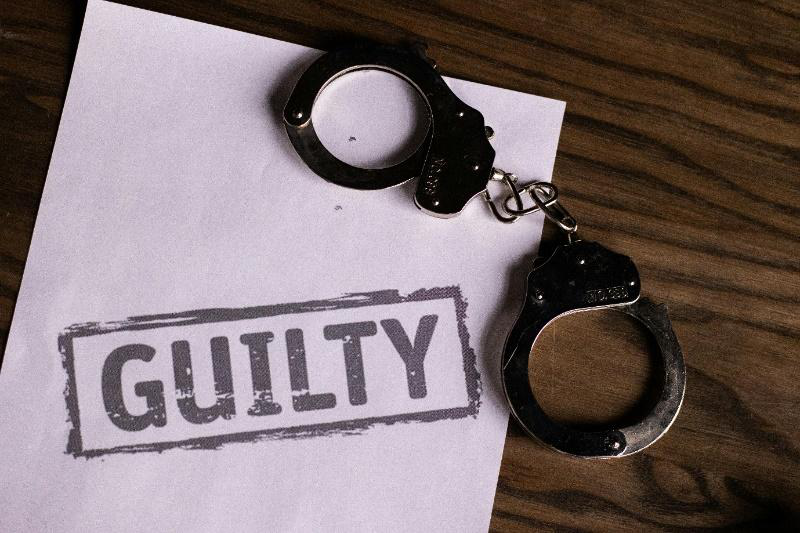 An image of handcuffs and a paper that says guilty